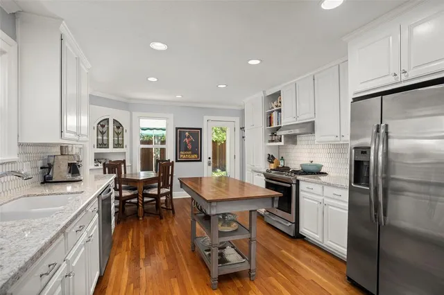 a kitchen with granite countertop kitchen island stainless steel appliances a stove a sink a refrigerator and cabinets