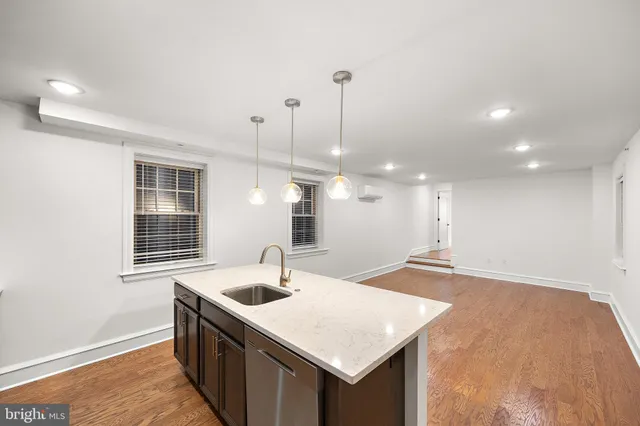 a kitchen with a sink a large window and wooden floor