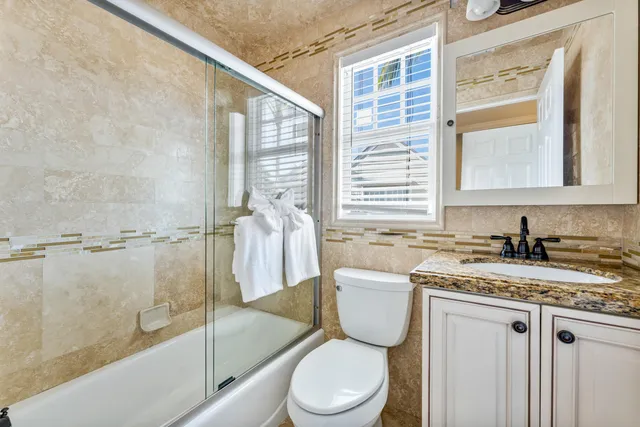 a bathroom with a granite countertop sink toilet and shower