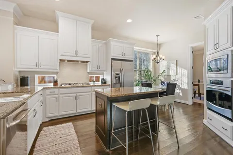 a kitchen with stainless steel appliances granite countertop a table chairs sink and cabinets