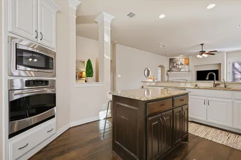 a kitchen with stainless steel appliances granite countertop a stove top oven a sink dishwasher and a microwave oven with wooden floor