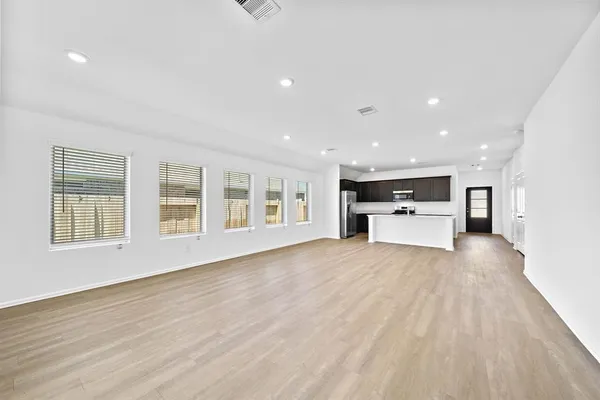 a view of empty room with kitchen and window
