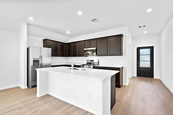 a kitchen with stainless steel appliances a refrigerator stove a sink and a oven with wooden floor