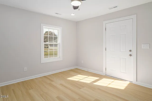 a view of empty room with wooden floor and fan