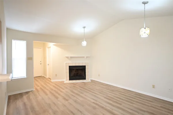 a view of empty room with wooden floor and fireplace