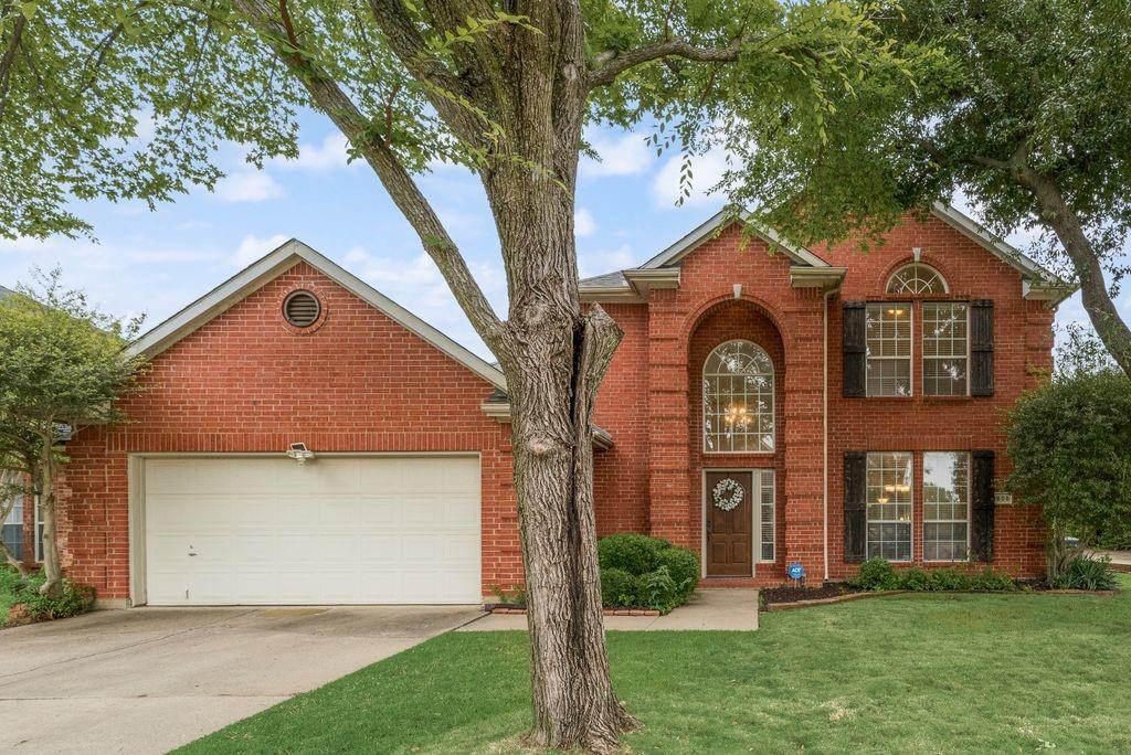 1605 Tree Line Road Flower Mound, TX 75028 - Photo 1 of 1 Traditional brick exterior featuring a two-story arched entry, dark wood front door, and a two-car garage