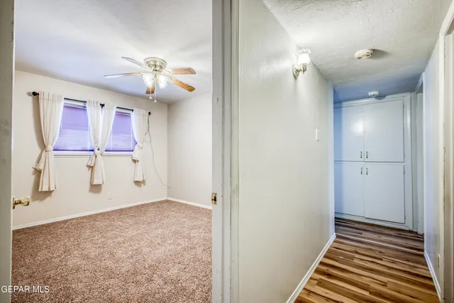 an empty room with windows and fan chandelier fan