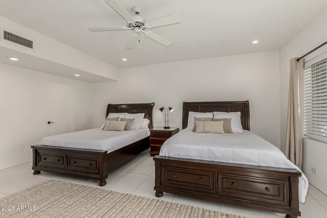 a bedroom with a bed table chair and window