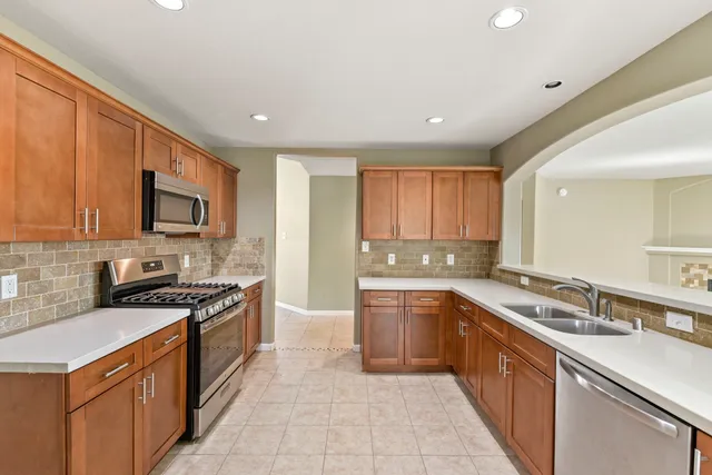 a large kitchen with stainless steel appliances granite countertop a stove sink and cabinets