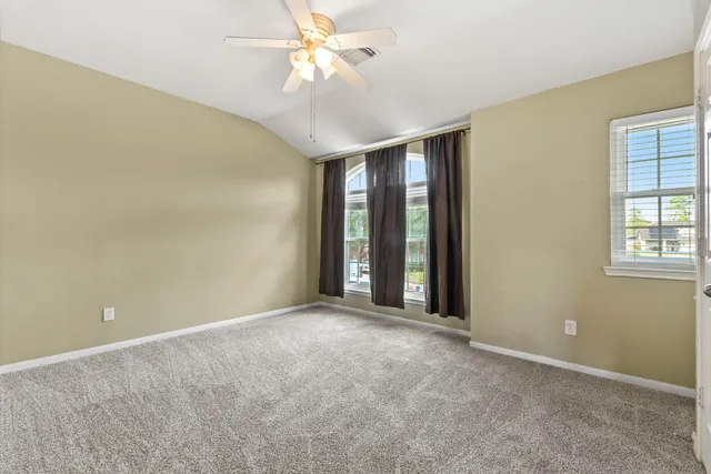 an empty room with windows and fan