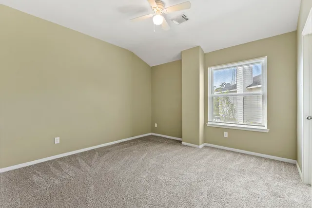 a view of an empty room with chandelier fan and fire place