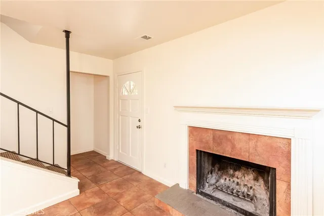 a view of an empty room with wooden floor fireplace and a window