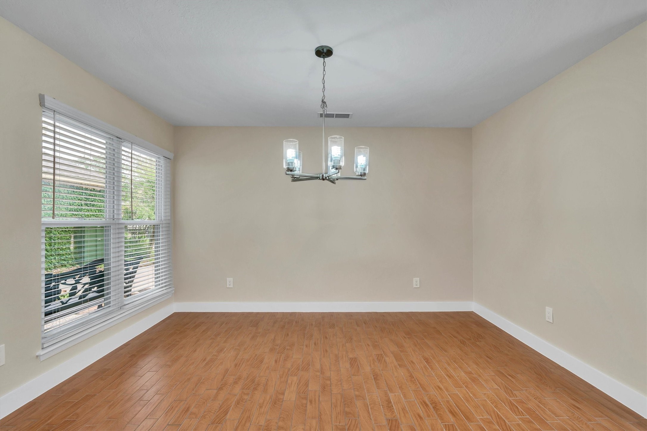 2163 Paso Rello Drive Houston, TX 77077 - Photo 10 of 45 This bright dining area features wood flooring, a modern chandelier, and large windows with blinds, allowing natural light to fill the space.