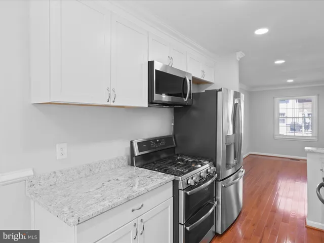 a kitchen with granite countertop a sink stainless steel appliances and white cabinets