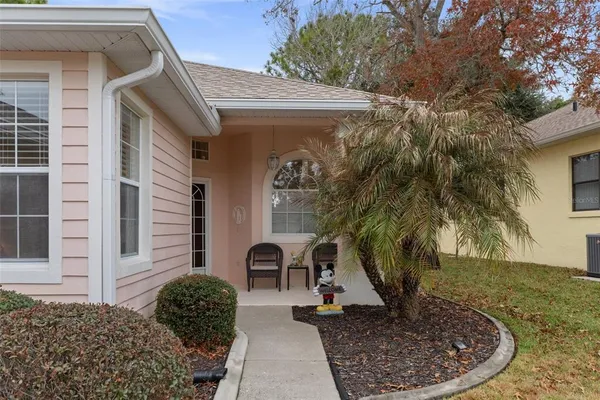 a view of a house with a yard potted plants and a bench
