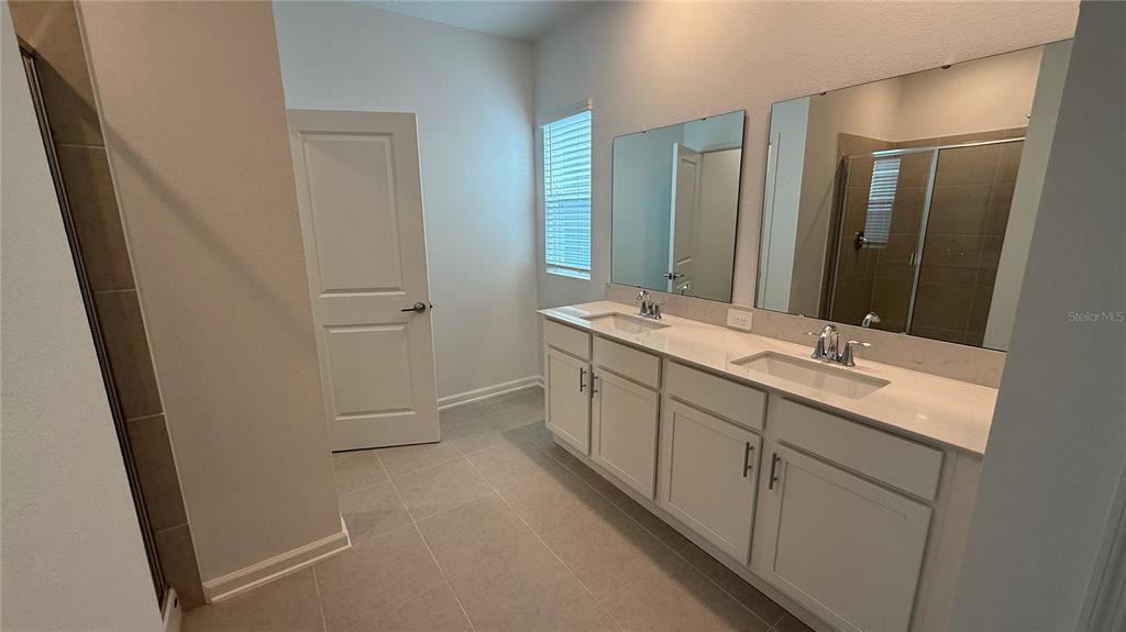 6045 Wellbeing Way Clermont, FL 34714 - Photo 17 of 19 a bathroom with a double vanity sink and mirror