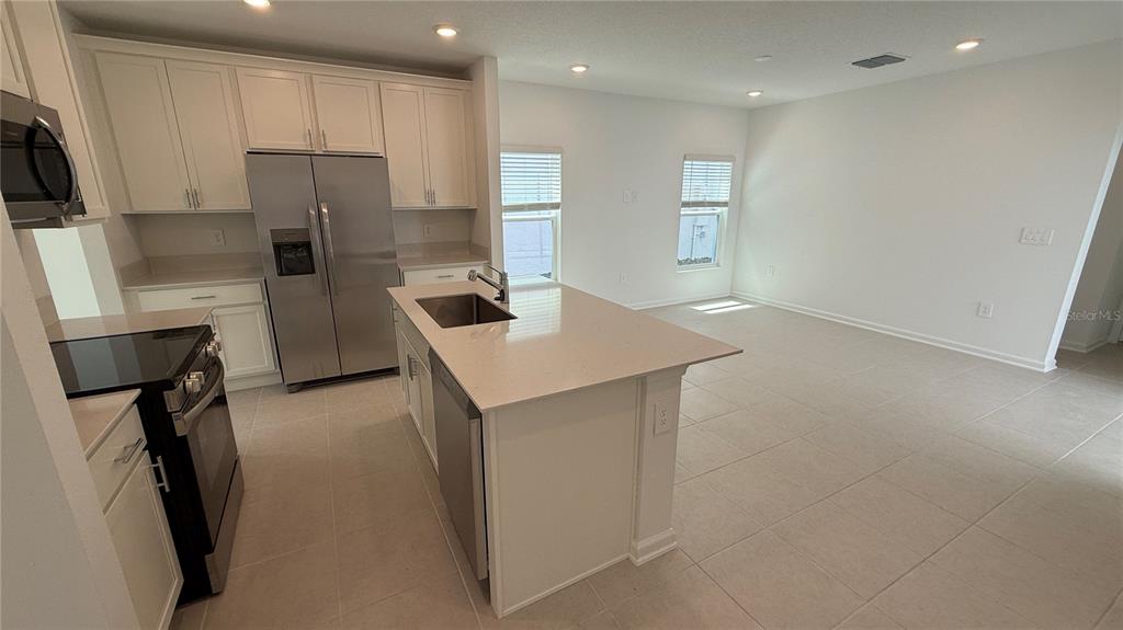 6045 Wellbeing Way Clermont, FL 34714 - Photo 2 of 19 a kitchen with refrigerator and chairs