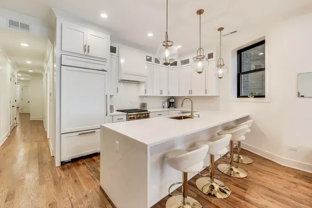 a large kitchen with kitchen island a stove a sink a refrigerator and a dining table with wooden floor