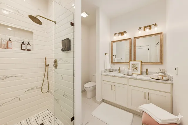 a bathroom with a granite countertop sink a toilet a mirror and shower