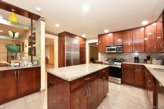 a kitchen with stainless steel appliances granite countertop a stove top oven a sink dishwasher and a refrigerator with wooden floor