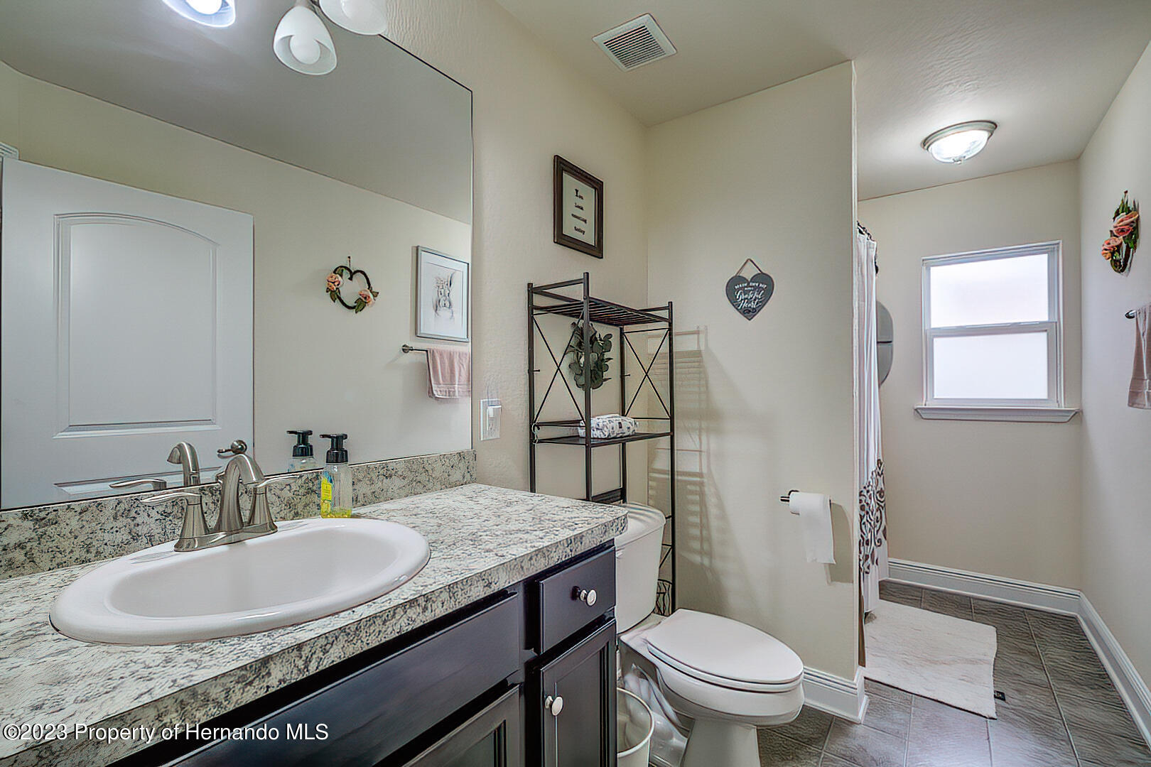 8140 Jasbow Junction Weeki Wachee, FL 34613 - Photo 21 of 37 a bathroom with a granite countertop toilet a sink and a mirror