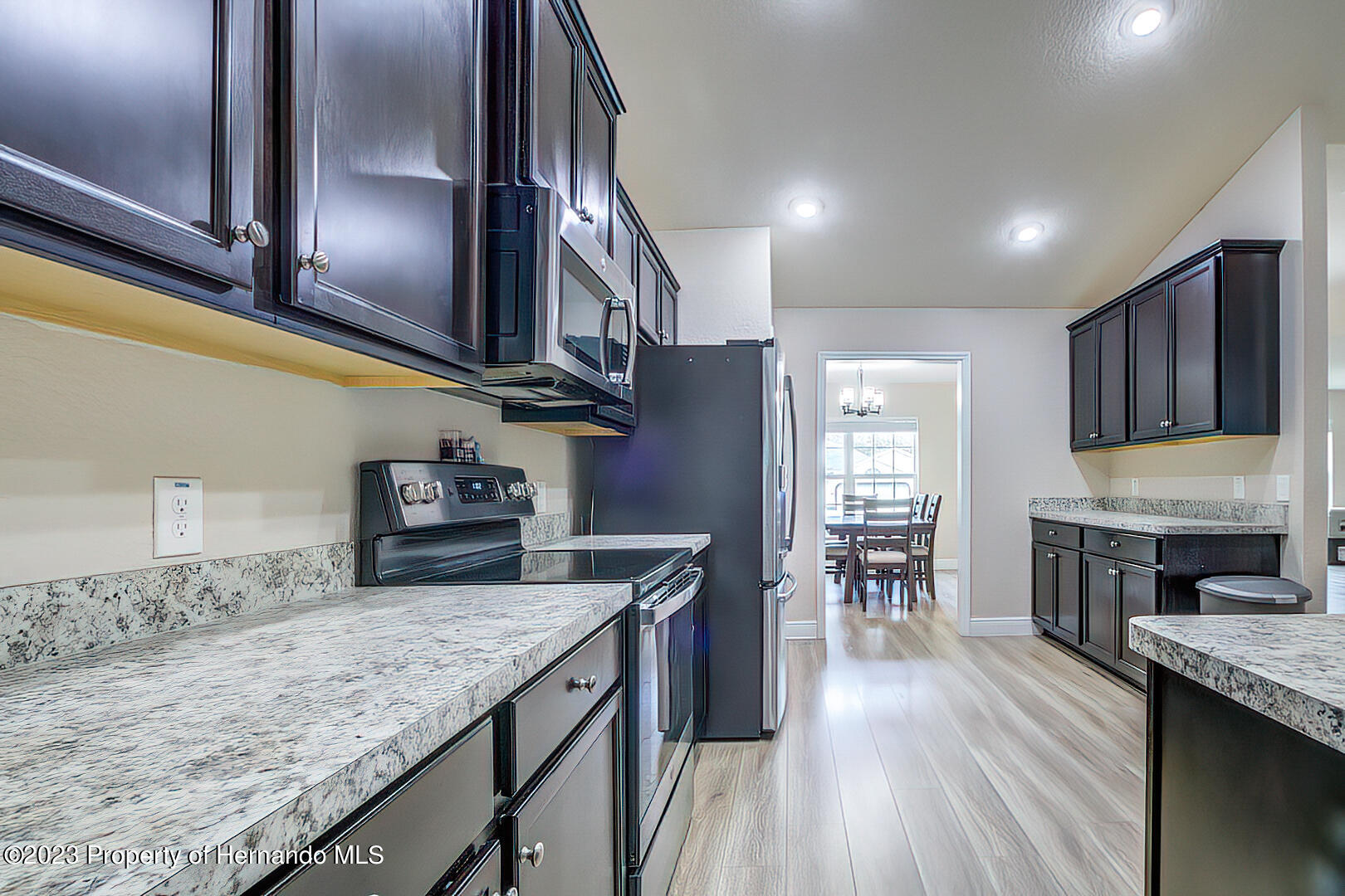 8140 Jasbow Junction Weeki Wachee, FL 34613 - Photo 9 of 37 a kitchen with stainless steel appliances granite countertop a lot of counter space and wooden floors