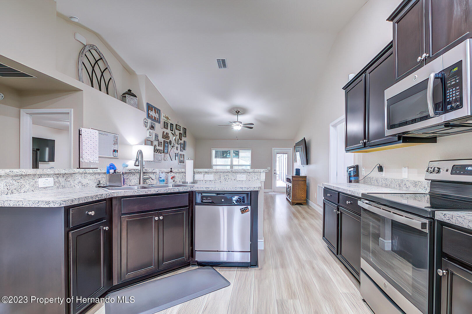 8140 Jasbow Junction Weeki Wachee, FL 34613 - Photo 10 of 37 a kitchen with stainless steel appliances granite countertop wooden cabinets a sink dishwasher a stove and a refrigerator