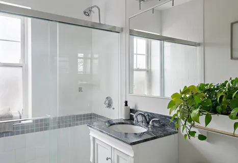 a bathroom with a granite countertop sink a mirror and a shower