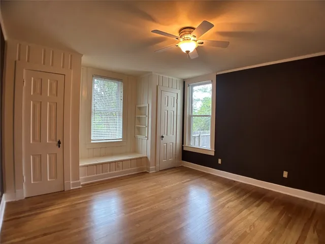 an empty room with wooden floor and windows