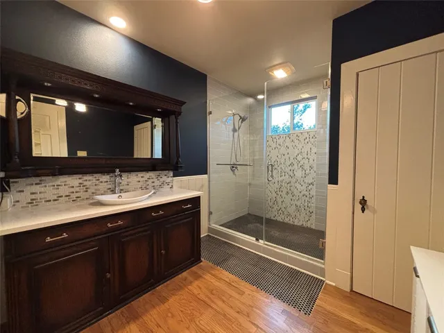 a bathroom with a granite countertop sink a mirror and a shower