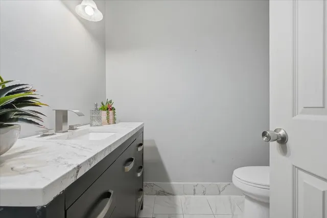 a bathroom with a granite countertop toilet sink and mirror