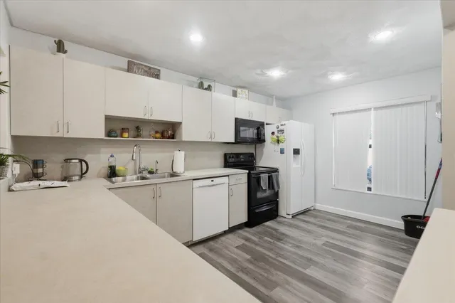 a kitchen with granite countertop a refrigerator stove top oven and sink