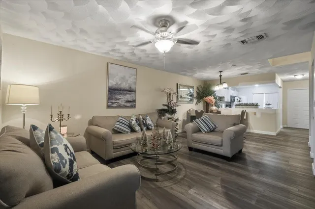 a living room with furniture kitchen view and a chandelier