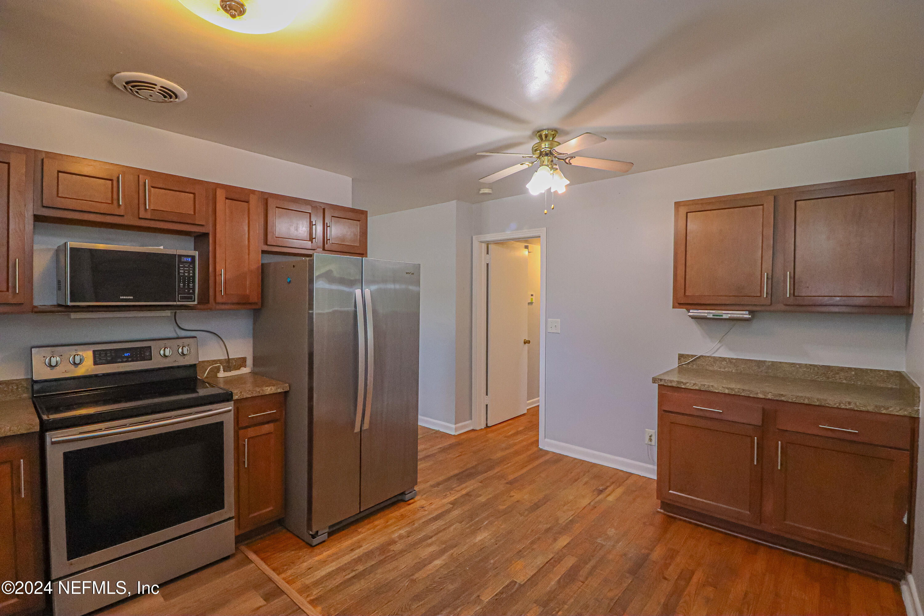 6503 Ector Road Jacksonville, FL 32211 - Photo 8 of 25 a kitchen with granite countertop wooden floors stainless steel appliances and a counter space