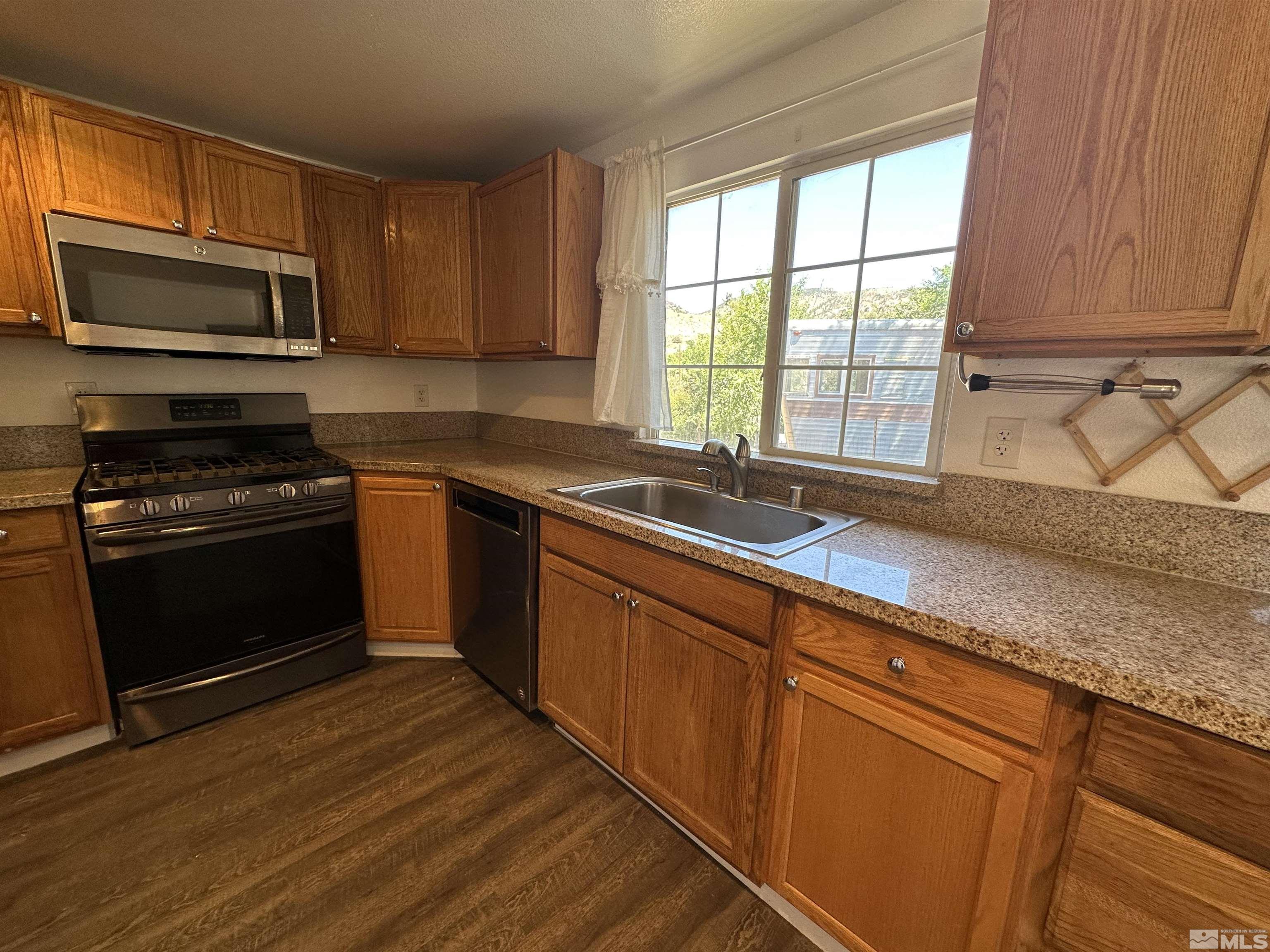 15119 Kivett Lane Reno, NV 89521 - Photo 6 of 20 a kitchen with granite countertop wooden cabinets appliances and a window