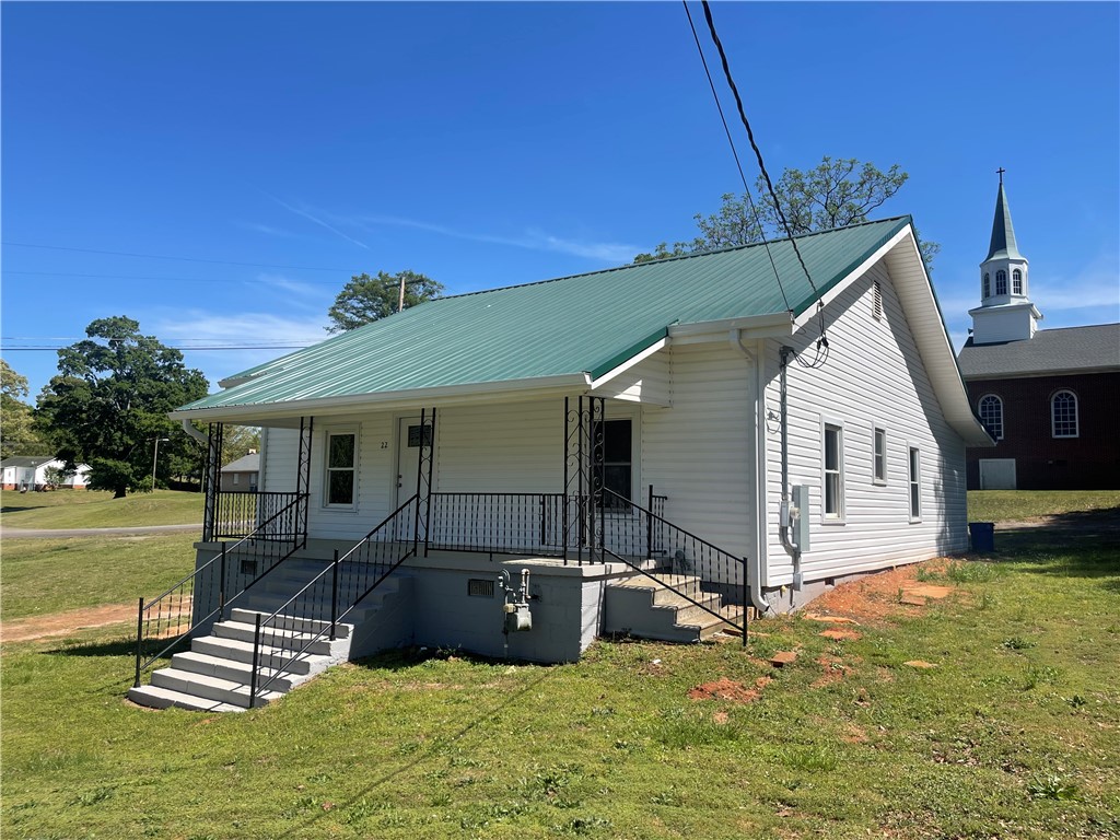 This charming home offers a quaint exterior with a vibrant green roof and welcoming porch.