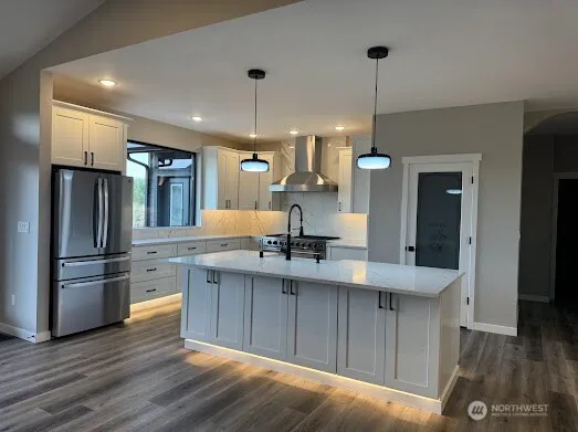 a kitchen with kitchen island a sink stainless steel appliances and wooden floor