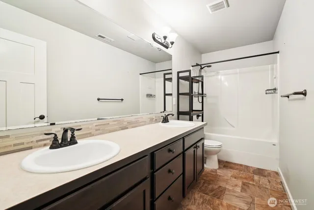 a bathroom with a double vanity sink toilet mirror and shower
