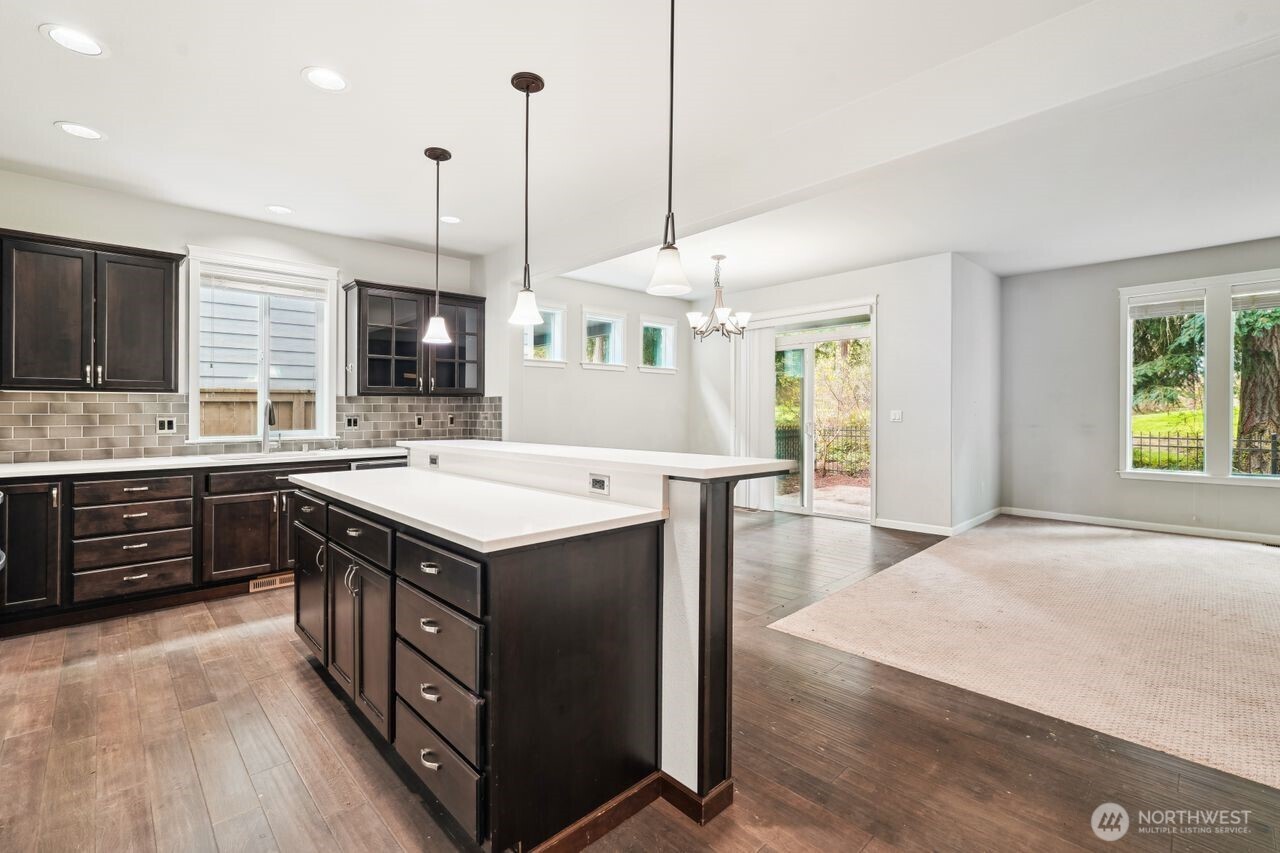 4335 Dudley Drive Northeast Lacey, WA 98516 - Photo 22 of 39 a kitchen with a stove a sink a microwave oven and a dining table with wooden floor