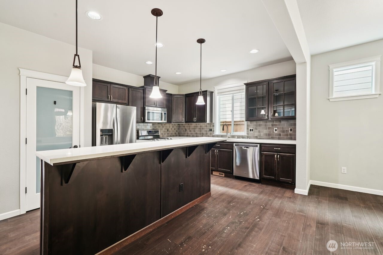 4335 Dudley Drive Northeast Lacey, WA 98516 - Photo 24 of 39 a open kitchen with stainless steel appliances granite countertop a stove a sink dishwasher a refrigerator and a wooden floor with potted plants
