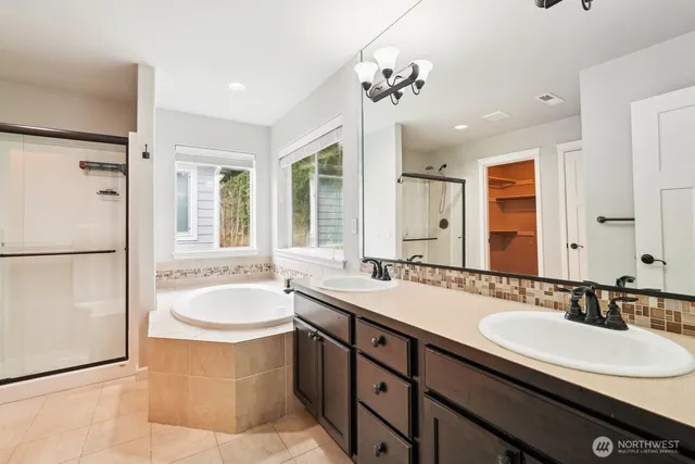 a bathroom with a tub a sink and a large mirror