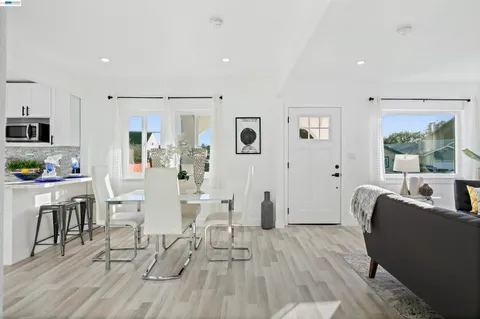 a kitchen with stainless steel appliances a dining table chairs and wooden floor