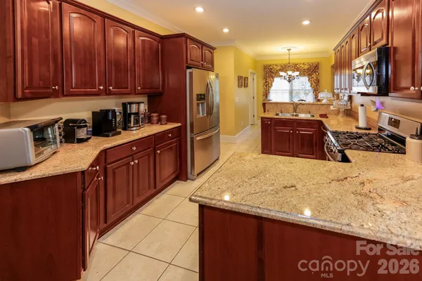 a kitchen with stainless steel appliances granite countertop wooden cabinets a refrigerator and a sink