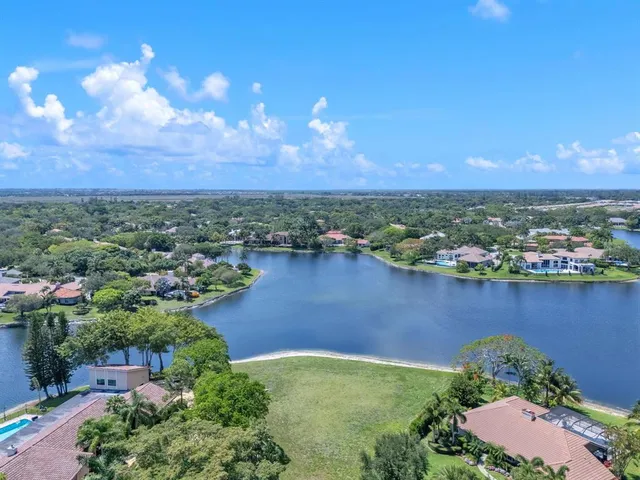 an aerial view of residential houses with outdoor space and lake view in back