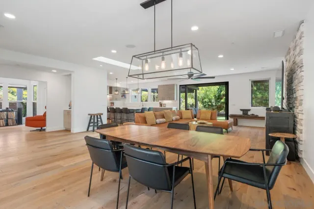 a dining room with wooden floor a chandelier a wooden table and chairs