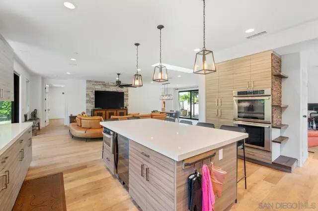 a large kitchen with kitchen island a stove a sink dishwasher and a fireplace with wooden floor