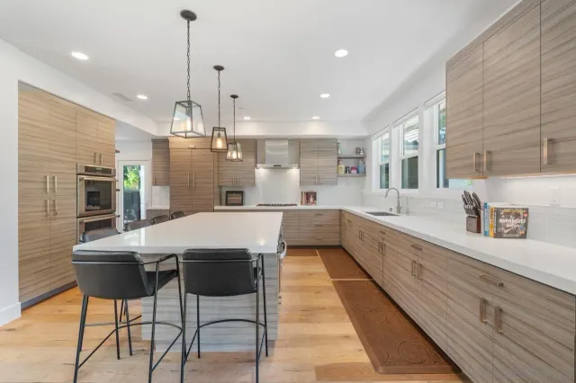 a large kitchen with kitchen island a large counter top and stainless steel appliances