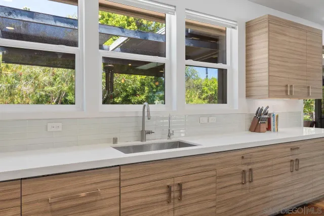 a bathroom with a sink and a large mirror next to a window