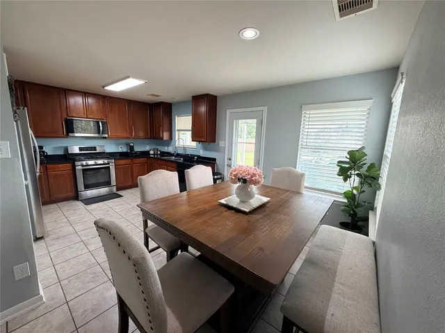 a kitchen with stainless steel appliances granite countertop a stove a sink a refrigerator a stove a dining table and chairs