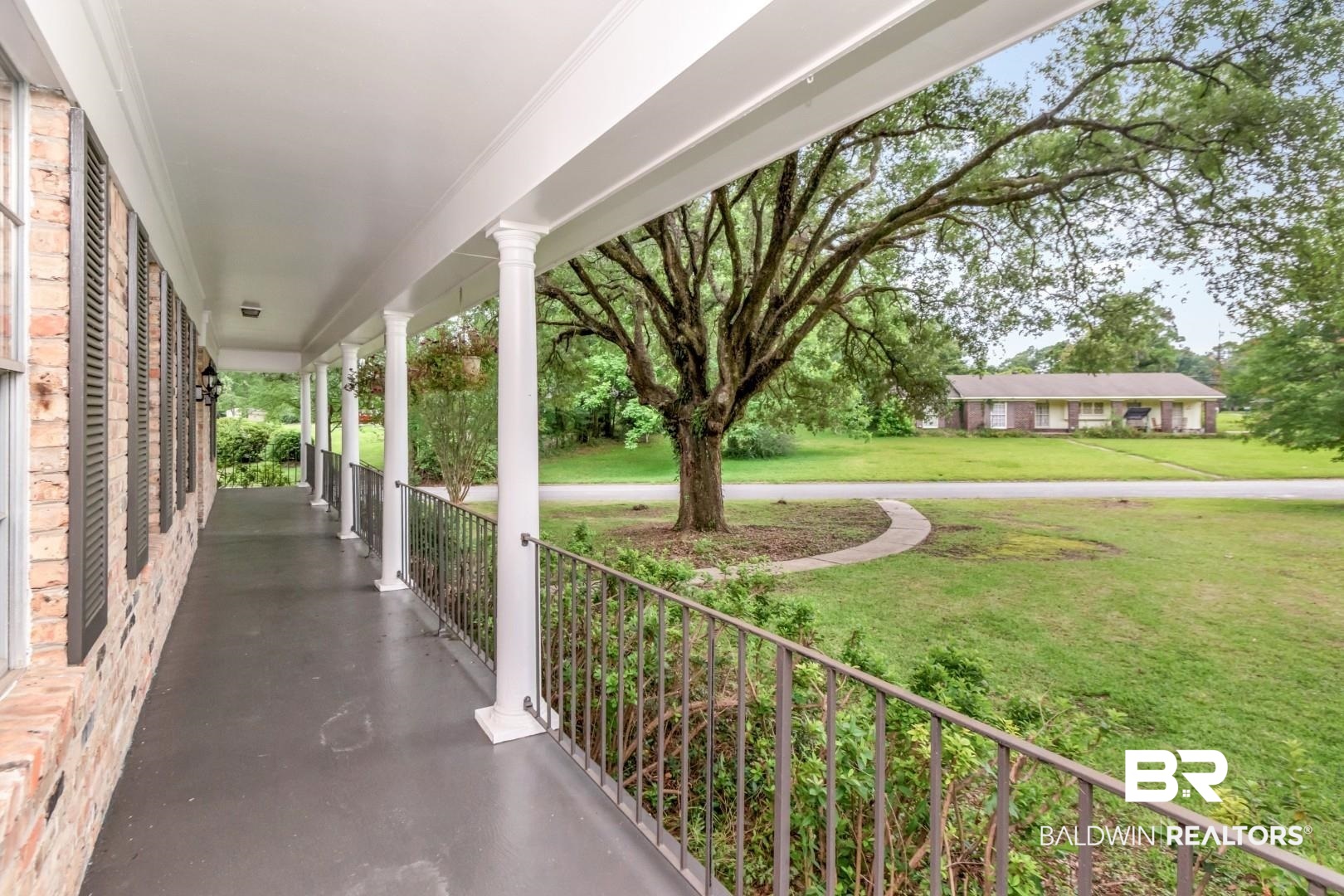 5217 Perin Road Mobile, AL 36693 - Photo 26 of 45 Covered front porch with white columns, dark railings, and a brick exterior